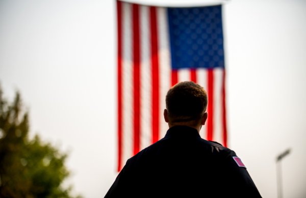 Firefighter silhouetted against U.S. flag