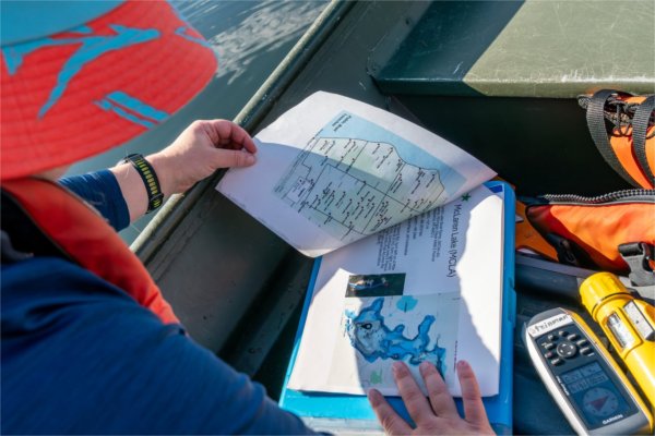 A person looks through papers on a blue clipboard.
