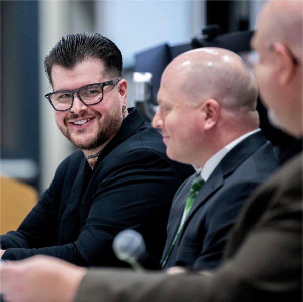 three men seated at a table, with microphones