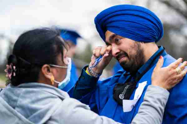 A student tears up while getting a hug from a family member during commencement celebrations