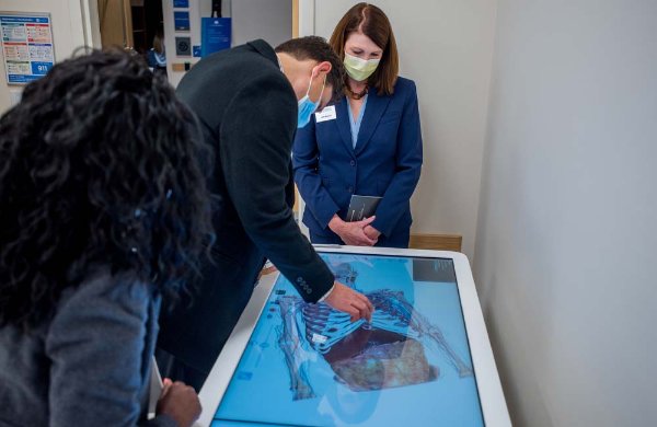 People gather around a large simulation tablet in DCIH