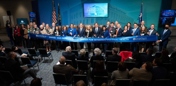 Several people line up behind a large ribbon inside of DCIH