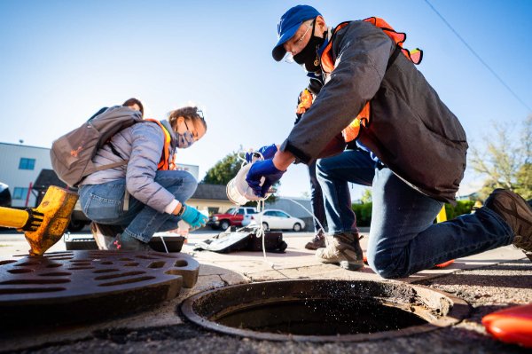 Researchers collect a water sample from the street