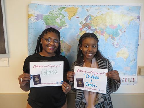 Vanesha Blackburn, left, and Alita Reneau hold signs for their study abroad programs. They, along with Jaedah Pickens, earned scholarships to apply for passports.