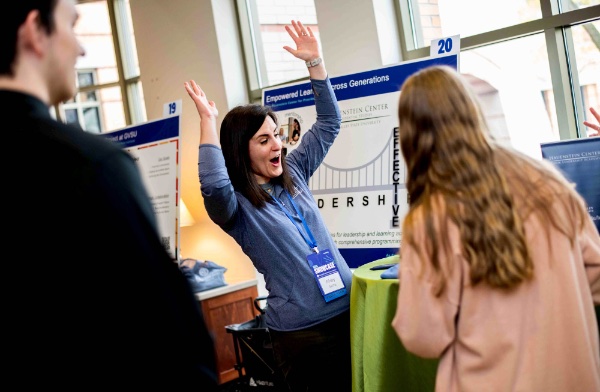 Abby Sachs, program manager with Peter C. Cook Leadership Academy, raises her arms in celebration as a student spins a game wheel at the Reach Higher Showcase booth April 21.