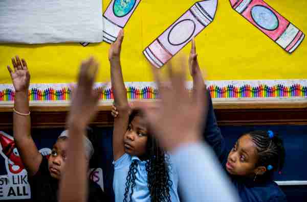 Students raising their hands during class at a Muskegon Heights school.