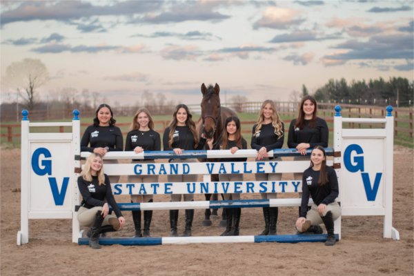 group of students in black shirts standing with horse, signage reads GVSU