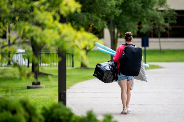 A student heads to her room holding all of her belongings. 
