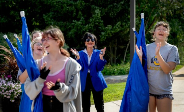 President Philomena V. Mantella joins the color guard of the Laker Marching Band during its rehearsal on August 26, 