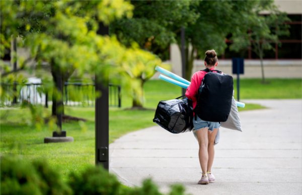 A student heads to her room holding all of her belongings. 