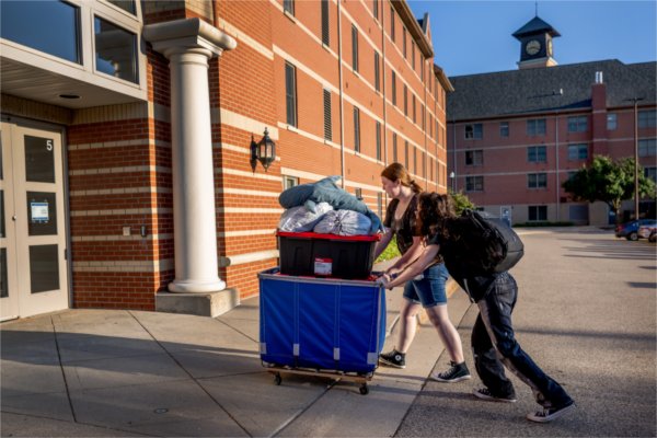 Gurby Lefebvre, right, pushes a cart of belongings into Winter Hall with the help of girlfriend Wren Petersen, center, during downtown move-in August 28. Lefebvre is a sophomore information technology major.
