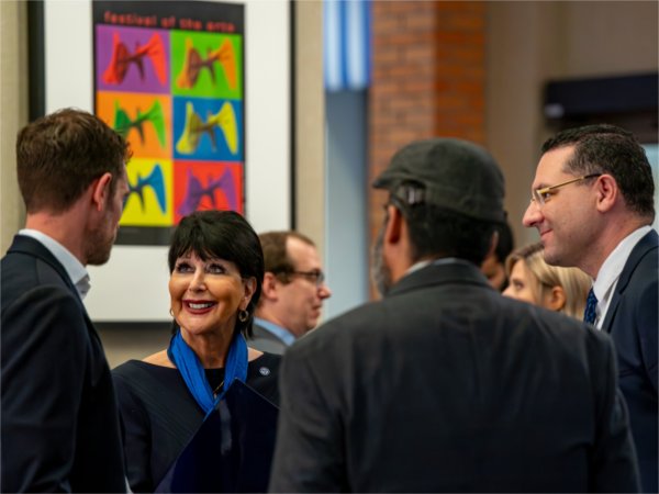 People smile while grouped together and talking at a gathering.