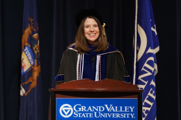 Provost Maria Cimitile addresses winter semester graduates during the virtual commencement ceremony. She is in academic regalia and behind a podium.