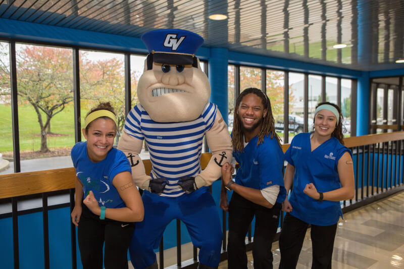 three students and Louie the Laker standing