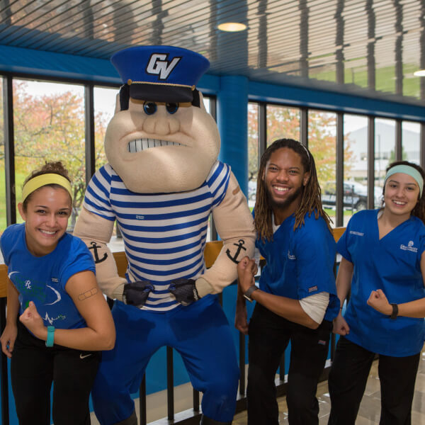 three students and Louie the Laker standing