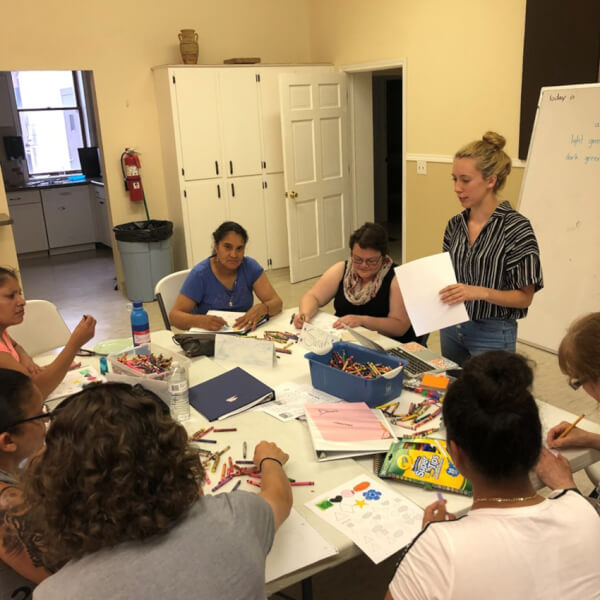women standing at table talking with adults who are seated