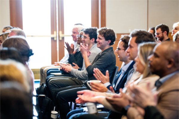 Ty Vanlerberghe, student senate vice president, center, claps along with other audience members during a press conference to share GVSU&#8217;s economic impact report.