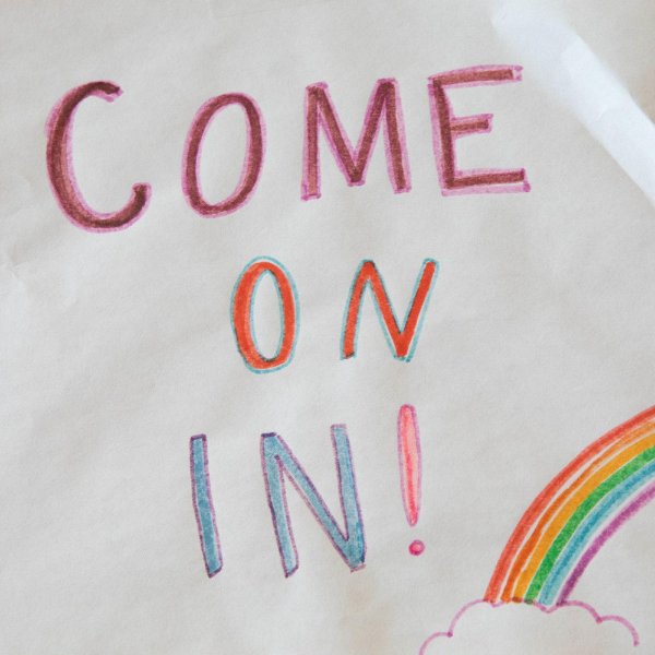 the words "come on in" written in crayon with a drawing of a rainbow.