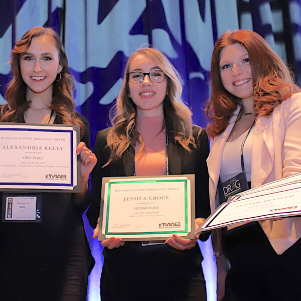 four students holding award certificates