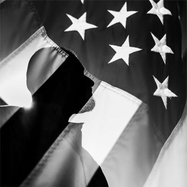 A silhouette of a person's side profile seen through an American flag.