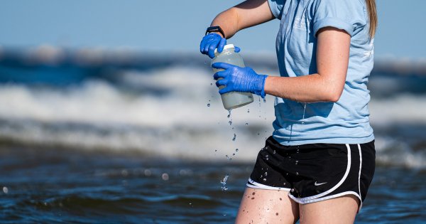 Lexy Porter samples water from Lake Michigan at Pere Marquette Beach in Muskegon