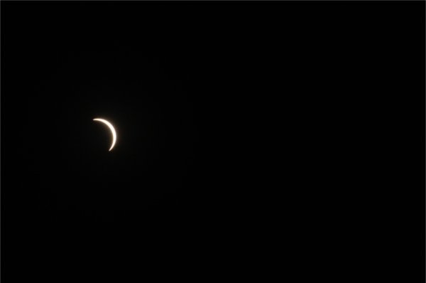 A sliver of sunlight is seen during a solar eclipse. The backdrop is dark.