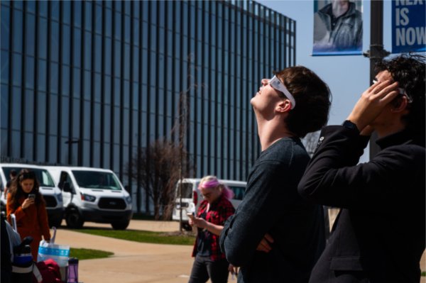 Two people wearing special glasses look skyward.