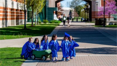 young preschool kids in blue caps and gowns on campus