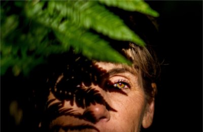 A person stands behind a leaf, with the sun and the shadow of the leaf showing.