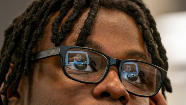 A screen depicting Dr. Martin Luther King, Jr. is reflected in a pair of glasses. 