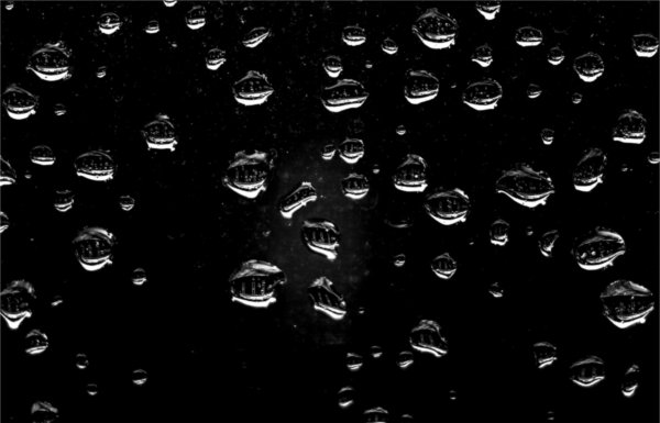  An academic building is seen reflected in water droplets that cling to a window. 