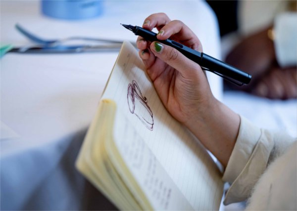  A person sketches a teacup into a journal. 