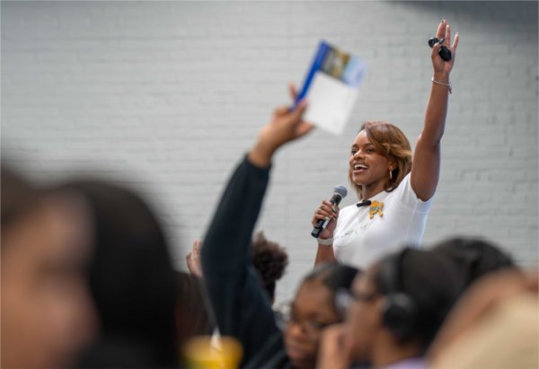 A person smiles as they hold their hand into the air during an event. 