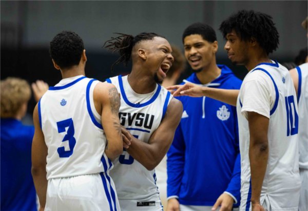 A college men's basketball team celebrate together. 