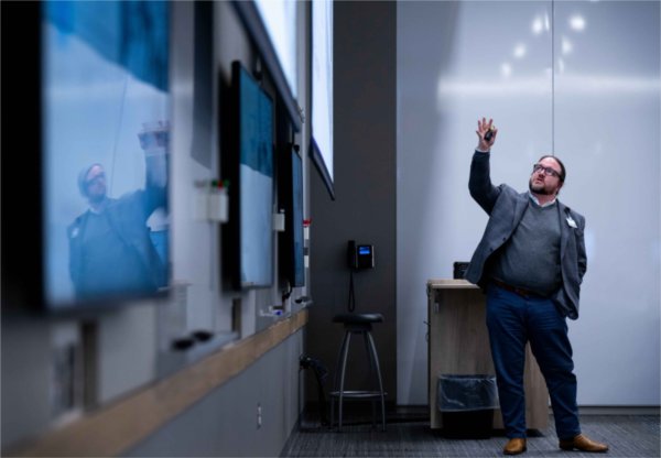 A Grand Valley college professor is reflected into a whiteboard while they talk to an audience.
