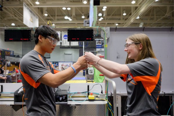 Two robotics students fist bump during a competition. 