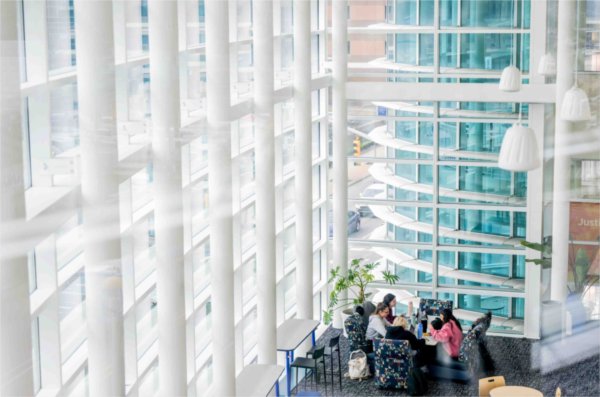 Architectural elements on a modern building highlight a group of students as they work together at a table. 
