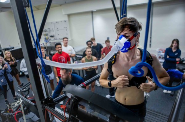  A person hooked up to a face mask with a hose extending from it performs a test during a classroom activity. 