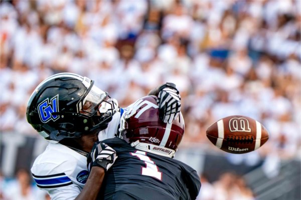  A football flies free from two players as they collide. 