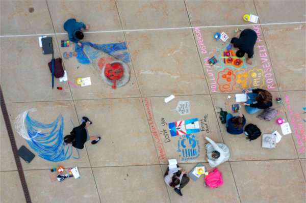 College students draw their research projects in chalk on the sidewalk. 