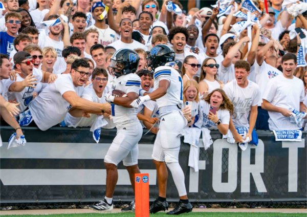  Football players share a moment with college fans after a touchdown. 