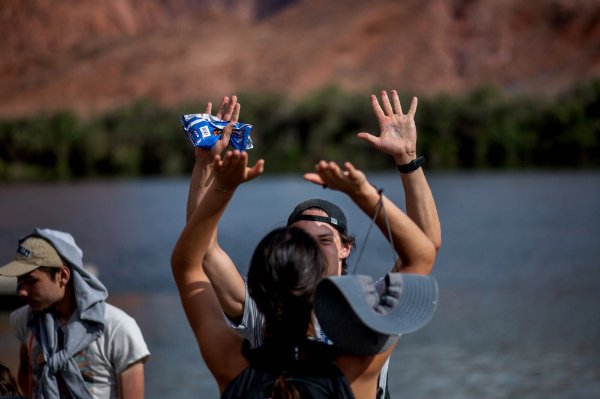 A person high-fives another person with a body of water in the background.