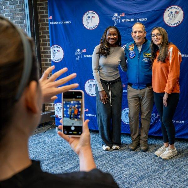 Former NASA astronaut John Herrington poses for a photo with two GVSU students.