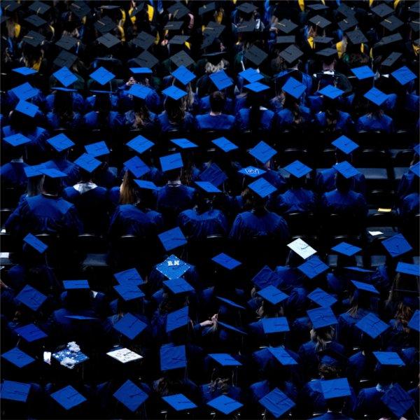Graduates wearing blue and black caps are seen from above.