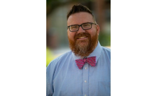Kevin Carmody, director of the Office of Institutional Equity and Title IX coordinator, in blue shirt and bow tie, standing outside