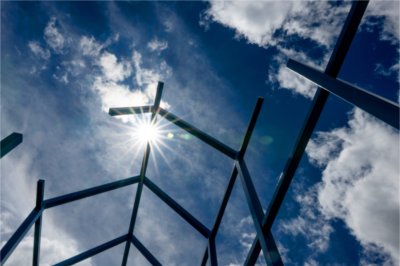 A blue metal sculpture is seen with a backdrop of a blue sky.
