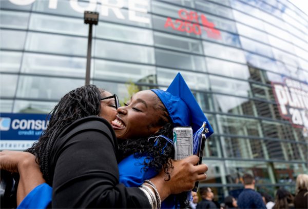  A mother and daughter hug after the daughter graduated wearing a blue cap and gown. 