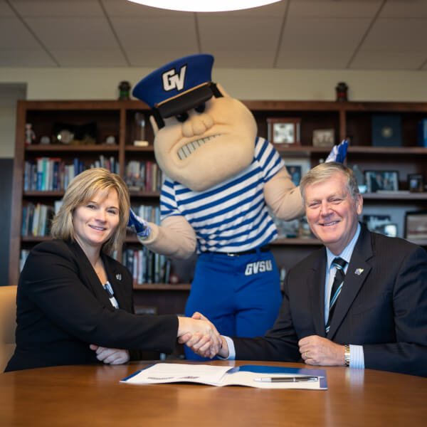 two people shaking hands Louie the Laker standing