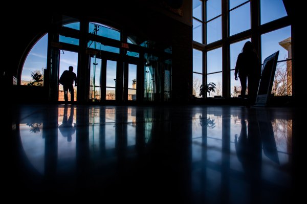  People are silhouetted as they walk through an entrance of a building.