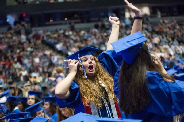  A college graduate pumps her fist and shouts while on a cellphone.
